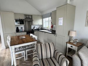 a kitchen with a table and a couch and a table at Sandy Collection - 2 next door beach houses - Part of the The Bay Filey Holiday Village with pool, gym and direct beach access, pub, restaurant, tennis and meadows walks in Filey +42 photos