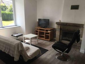 1 dormitorio con chimenea, silla y TV en Maison au calme récemment rénovée en Lescouët-Jugon