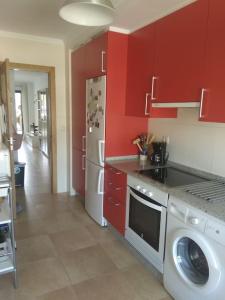 uma cozinha com armários vermelhos e uma máquina de lavar roupa em S, con piscina en Sanxenxo em Sanxenxo