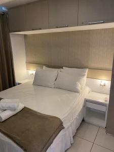 1 dormitorio con 1 cama grande con almohadas blancas en VG Sun Cumbuco Apto, en Cumbuco