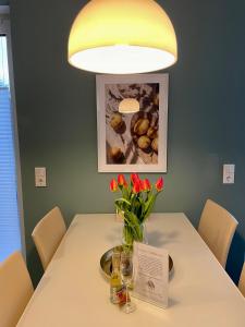 een tafel met een vaas met rode bloemen erop bij Feriendomizil Möhne mit Seeblick und Sauna in Möhnesee