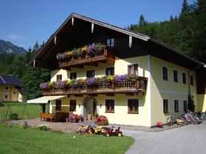 una casa amarilla con un balcón con flores. en Pferdehof Almgut en Faistenau