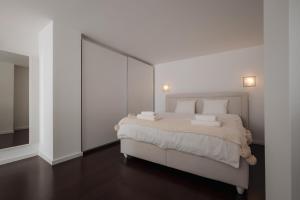 1 dormitorio con 1 cama grande y paredes blancas en SKAU Eurovea Duplex Apartment Danube Exclusive View Free Parking, en Bratislava