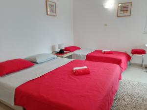 two beds in a room with red covers on them at Splendid studio apartment in Bečići