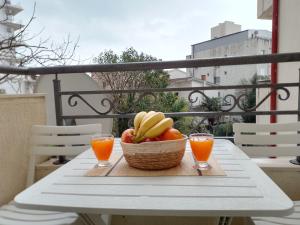 a basket of fruit on a table with two glasses of orange juice at Splendid studio apartment in Bečići