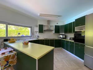 a kitchen with green cabinets and a yellow counter top at Villa 96 Golf de la Baule avec piscine et spa in Saint-André-des-Eaux