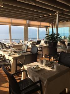 a restaurant with white tables and chairs with a view of the ocean at Hotel La Terrazzina in Gargnano