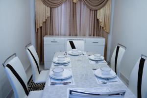 a dining room with a table and chairs with plates and dishes at Dolly Apartments in Nairobi