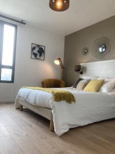 um quarto com uma grande cama branca com almofadas amarelas em Appart'Hotel - Gare TGV - Courtine - Confluence - 218 em Avignon