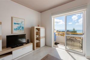 a living room with a tv and a large window at Seafront 2 bedroom apart with air con and garage in Armação de Pera in Armação de Pêra