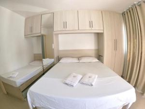 1 dormitorio con 1 cama blanca y 2 toallas en Cabo Frio Lindo 2 quartos Reformado para 8 pessoas, en Cabo Frío