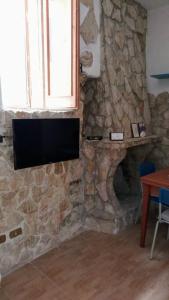una chimenea de piedra con TV en una pared de piedra en CASA FIORITA en Rodi Garganico