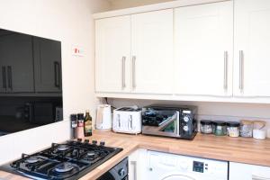 a kitchen with a stove top oven next to a microwave at Bee Stays - Maliston House in Great Sankey