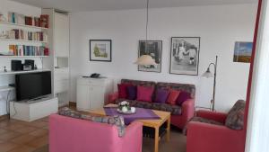 a living room with pink couches and a tv at Juist - Freund, FeWo Inselresidenz Wattenmeer Wo3 in Juist