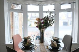 a dining room table with a vase of flowers on it at Bee Stays - Maliston House in Great Sankey