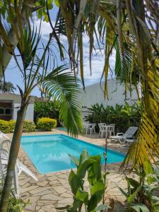 a swimming pool with chairs and a palm tree at Hotel Portal da Praia in Barequeçaba