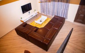 sala de estar con sofá de cuero marrón y TV en Urban Condos, en Accra