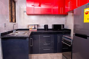 a kitchen with red cabinets and a sink at Urban Condos in Accra