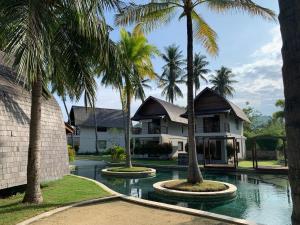 une maison avec des palmiers devant elle dans l'établissement The Club Villas Lombok, à Sekotong