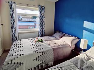 1 dormitorio con cama y pared azul en Sherlock's house - 4 spacious bedroom 8 beds Private free parking & WIFI Accessibility Contractors Family with children & pets welcome en Burton upon Trent
