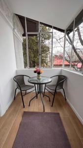 stół i krzesła w pokoju z oknami w obiekcie Charming Place Cotroceni w Bukareszcie