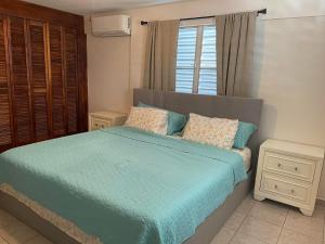 a bedroom with a bed with blue sheets and a window at Beautiful Villa 5 mins from Crash Boat Aguadilla 1 in Aguadilla