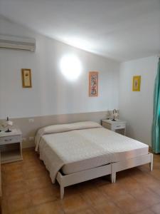 a white bedroom with a bed and two night stands at Il Falconiere in Muravera