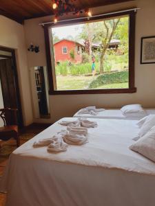 Schlafzimmer mit einem Bett und einem großen Fenster in der Unterkunft Capricho Asturiano in Santo Antônio do Leite