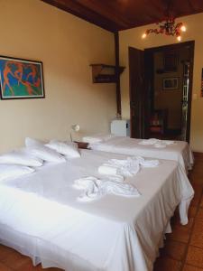 a group of three white beds in a room at Capricho Asturiano in Santo Antônio do Leite