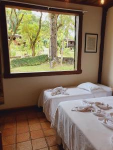 two beds in a room with a large window at Capricho Asturiano in Santo Antônio do Leite
