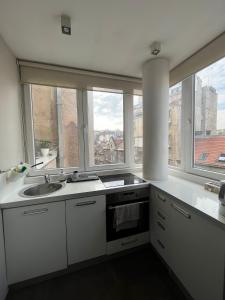 a kitchen with white counters and windows and a sink at DELUXE Apartment Newsky with terrace in Belgrade