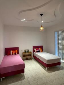 duas camas num quarto com rosa e branco em Magnifique villa vue mer em El Mida