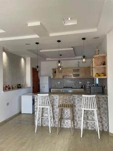 uma cozinha com dois bancos de bar e um balcão em Magnifique villa vue mer em El Mida
