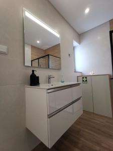 La salle de bains blanche est pourvue d'un lavabo et d'un miroir. dans l'établissement Cool Residence, à Portimão