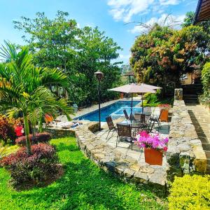 um quintal com uma piscina e uma mesa com um guarda-sol em Hotel Casas de Campo El Ciruelo em San Gil