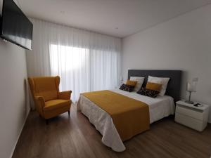- une chambre avec un lit, une chaise et une télévision dans l'établissement Cool Residence, à Portimão