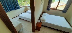 a small bedroom with two beds and a window at Oceano Pousada - Buffet de café da manhã e serviço de quarto diário in Bombinhas