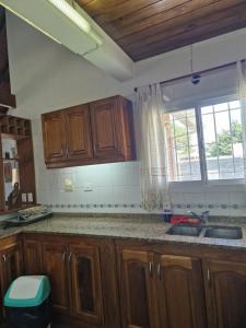 a kitchen with wooden cabinets and a sink and a window at Dunas Chalet y Apartamento, sólo familias in Pinamar +49 photos