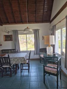 a dining room with a table and chairs and windows at Dunas Chalet y Apartamento in Pinamar