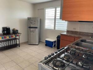 a kitchen with a stove and a stainless steel refrigerator at Beautiful Villa 5 mins from Crash Boat Aguadilla 1 in Aguadilla