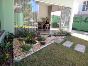 une femme assise dans une chaise sur la terrasse couverte d'une maison dans l'établissement Quatro suítes com piscina,1,7 km do centro de Arraial, à Arraial d'Ajuda