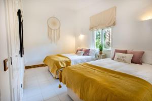 two beds in a room with yellow sheets at Maria Lisboa in Almancil