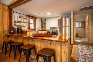 a kitchen with a counter with stools and a refrigerator at Hike the Holler - Stay & Explore in Cosby