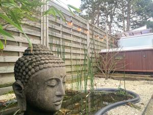 uma estátua de uma cabeça num jardim em Bed & breakfast Duna met hammam, jacuzzi, sauna em Koksijde