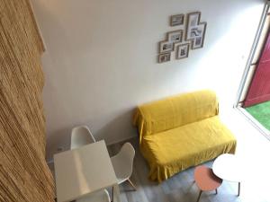 Habitación con cama amarilla, mesa y sillas. en Joli appartement à proximité du village naturiste en Cap d'Agde