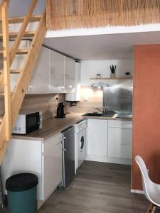una pequeña cocina con armarios blancos y una escalera en Joli appartement à proximité du village naturiste en Cap d'Agde