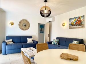 salon z niebieskimi kanapami i stołem w obiekcie Appart spacieux ,lumineux ,proche des plage , piscine w mieście Les Issambres