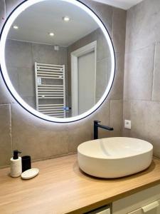 W łazience znajduje się duże okrągłe lustro i umywalka. w obiekcie Appart spacieux ,lumineux ,proche des plage , piscine w mieście Les Issambres +13 zdjęć