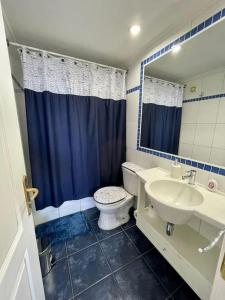 a blue and white bathroom with a toilet and a sink at Departamento Frente a Espacio Grecia, Calama. in Calama