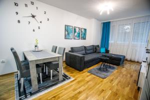uma sala de estar com um sofá e uma mesa em Tik Tak apartman em Subotica